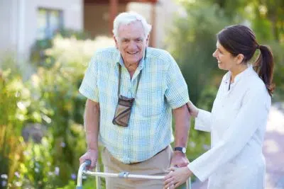 une personne agée en déambulateur avec un docteur en promenade