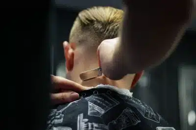 person trimming man's hair